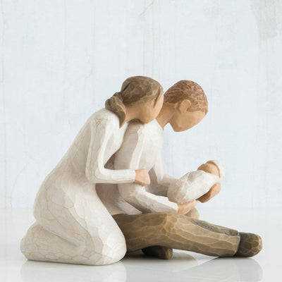 New Life: Willow Tree with seated couple holding a newborn baby Woman in cream dress, man in cream shirt and dark pants, baby in cream blanket